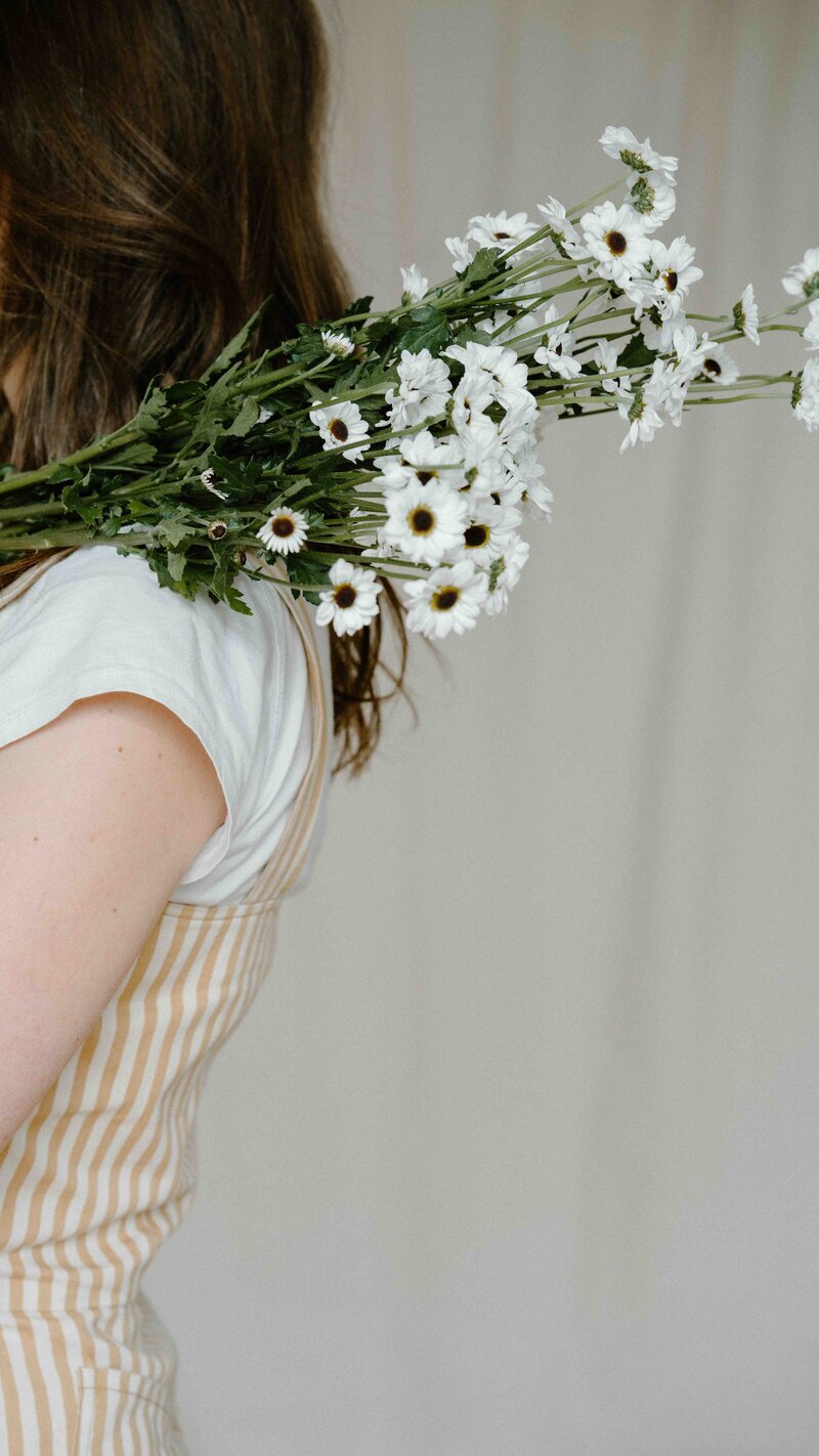 Bouquet of daisies over woman's shoulder