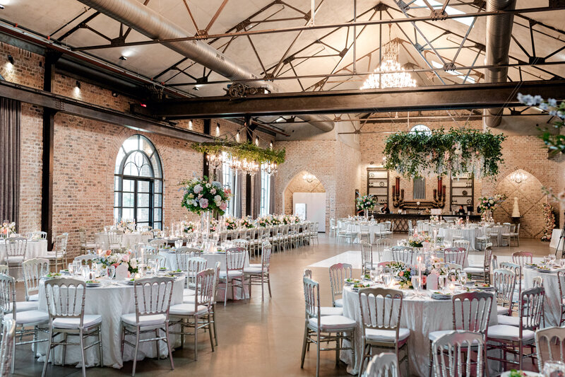 Bride and groom kissing with their reception and guests in the background