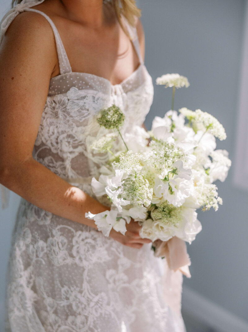 Bride holding a romantic white bridal bouquet with queen anne’s lace and sweet peas at private venue in Maryland. Luxury wedding flowers by Springvale Floral, editorial florist serving DC, Virginia, and Maryland.
