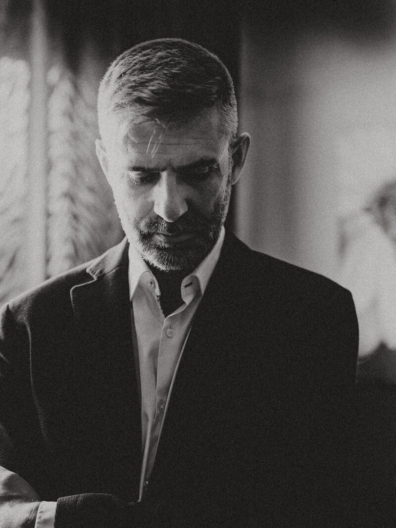 Black and white portrait of a Boris Tepeshanov in a button-down shirt with arms crossed against a wall background.