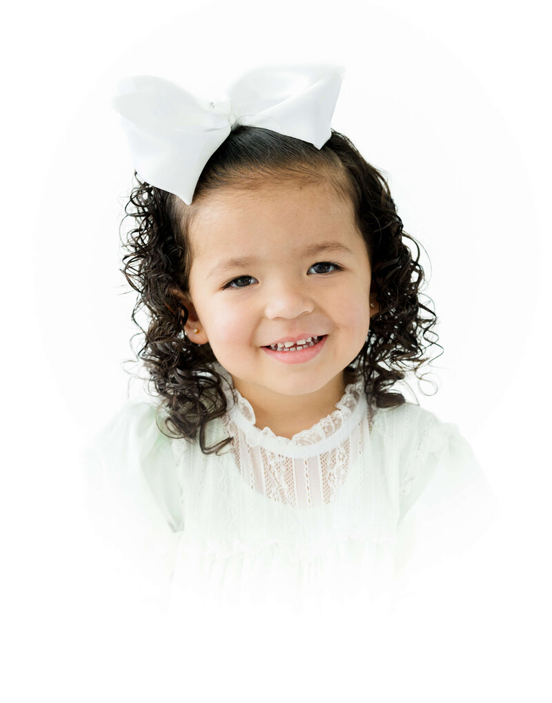 Girl sitting with bow smiling at camera for heirloom photos during mini model rep program