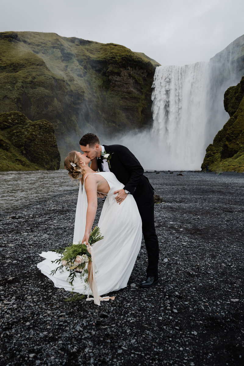 Bride and groom kissing during their elopement at Skogafoss waterfall in Iceland