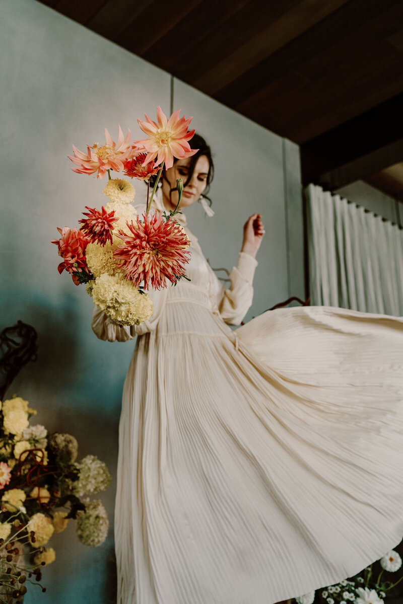 Bride swishing her dress with bouquet of flowers