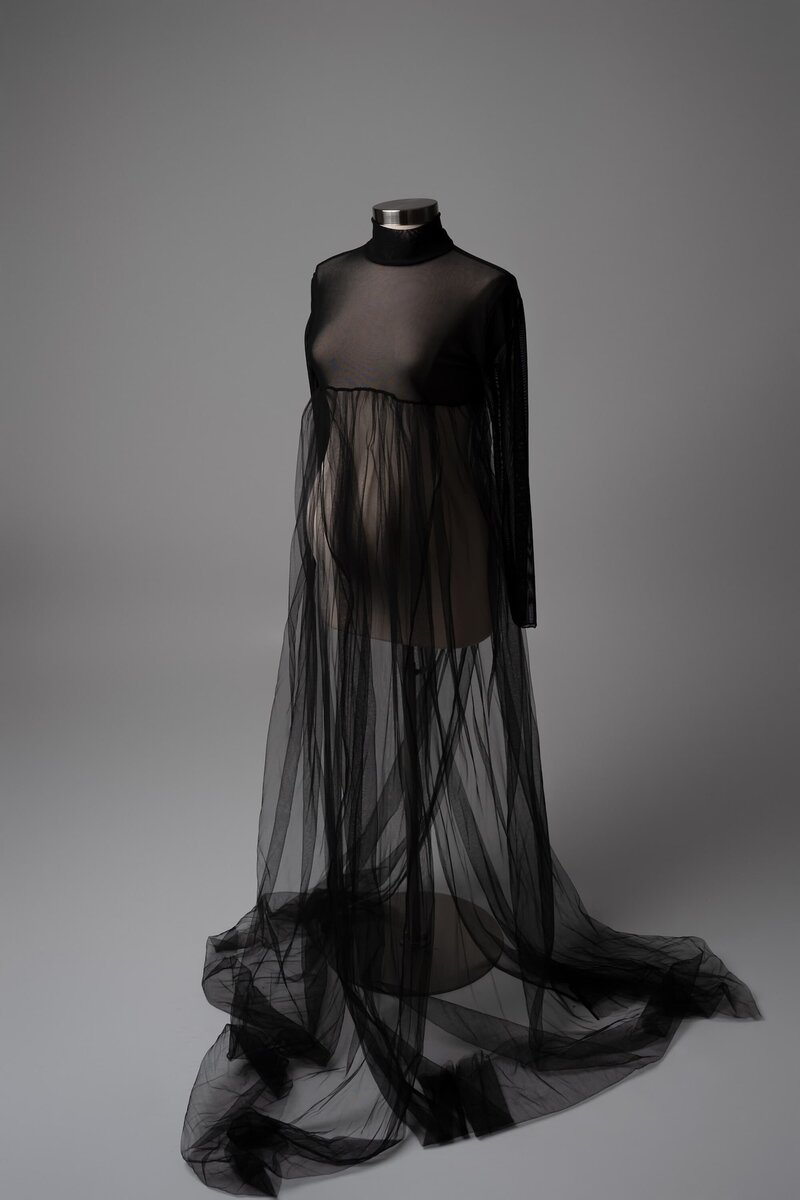 Sheer black gown with layered tulle and long sleeves on mannequin