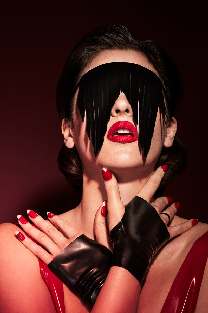 Artistic portrait of Hannah Cruz with dramatic red makeup and accessories, captured by Ylva Erevall.