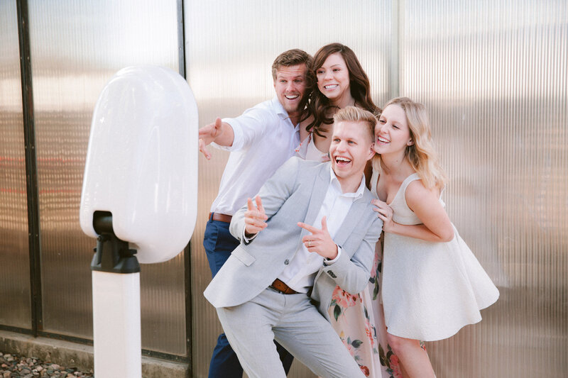 Two boys in a grey suit and white button down and two girls in white dresses smiling at the Charlotte photo booth
