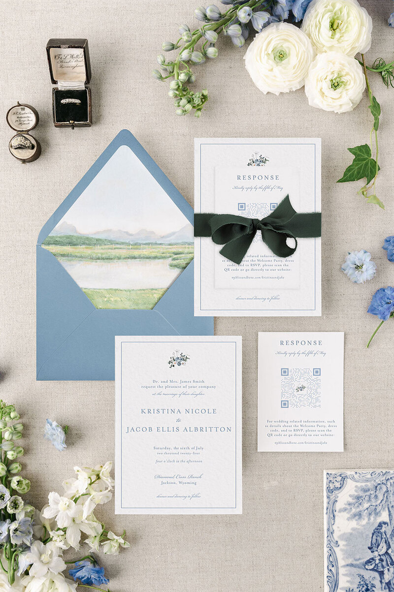 Letterpress wedding invitations with watercolor venue envelope liner in a blue envelope, and tied together with hand-dyed silk ribbon.
