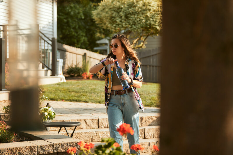 woman walking while opening a bottle