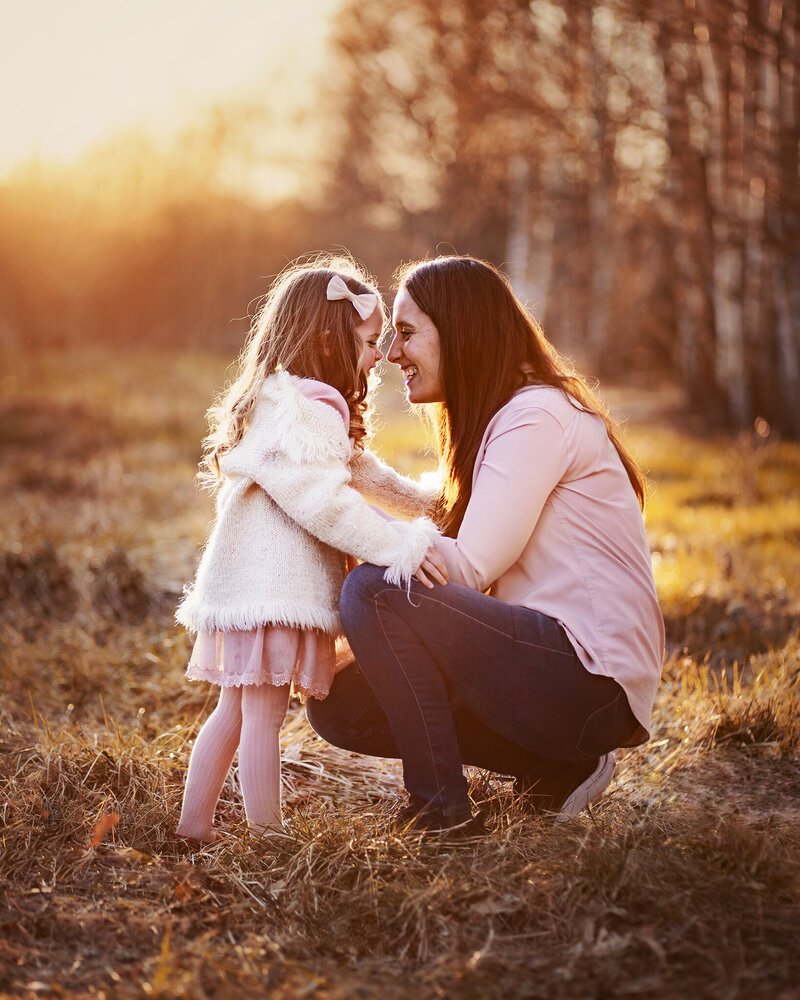 mamma och dotter näspussas i solnedgången