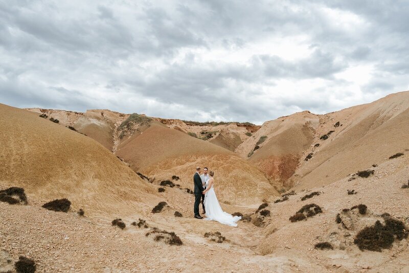 A bride and groom standing in a valley with barren cliffs in South Australia