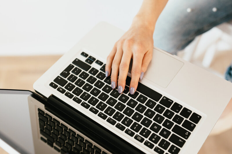 Social media manager typing on a laptop, creating content for clients.