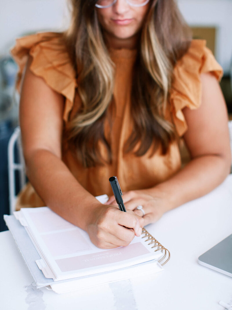 a woman sitting at a desk writing in a planner