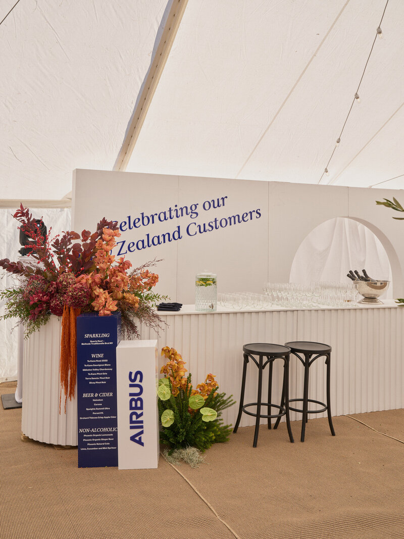 blue and white plinth bar signage with complimentary florals at a corporate event in glendhu bay, Wanaka