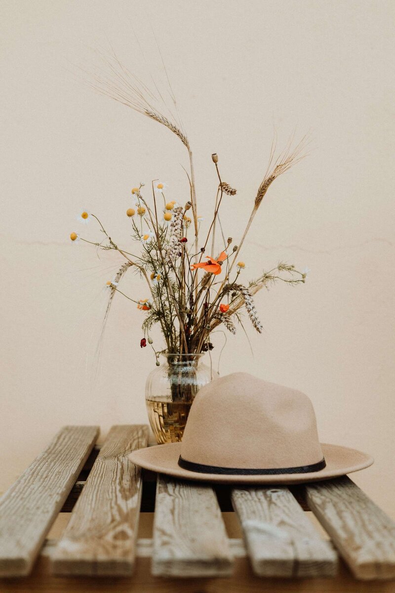 Hat with flowers in vase on a bench