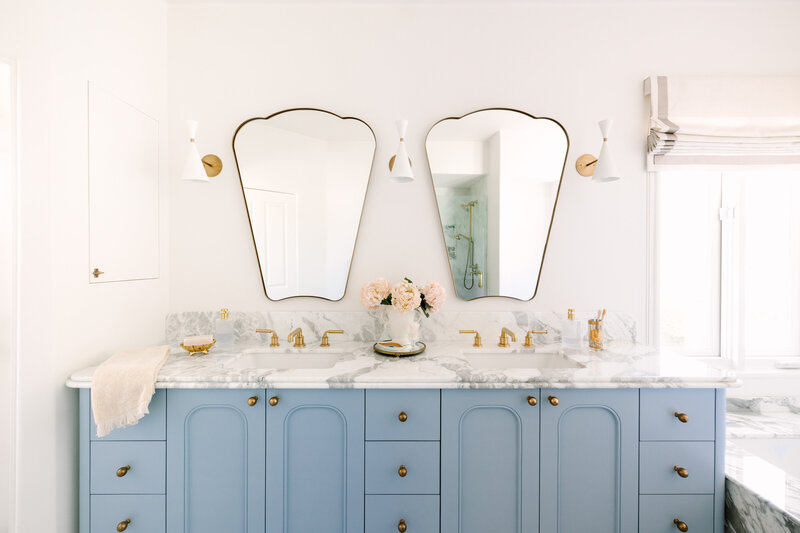 Kitchen with teal cabinets, Calcutta Gold marble counter and backsplash farm house sink and white and gold blue start hood and range.