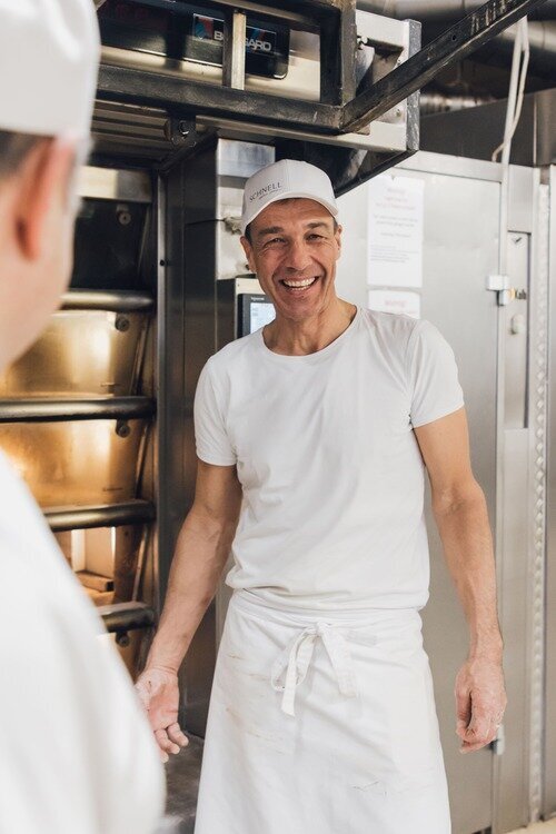 Inhaber und Bäcker Wolfgang Müller kippt Zutaten aus einer Wanne in den Mixer