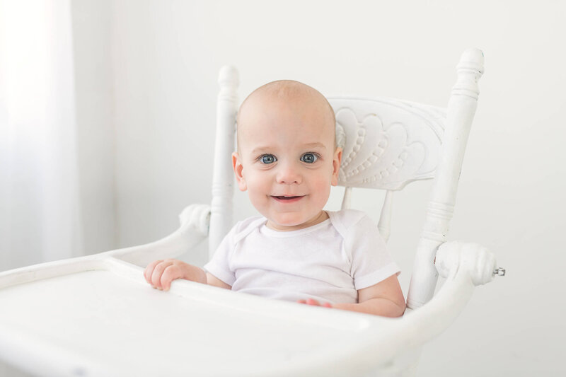 one year old in highchair smiles