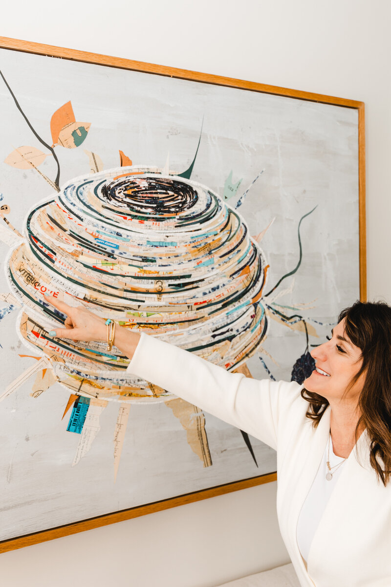 Dena pointing at artwork in her office