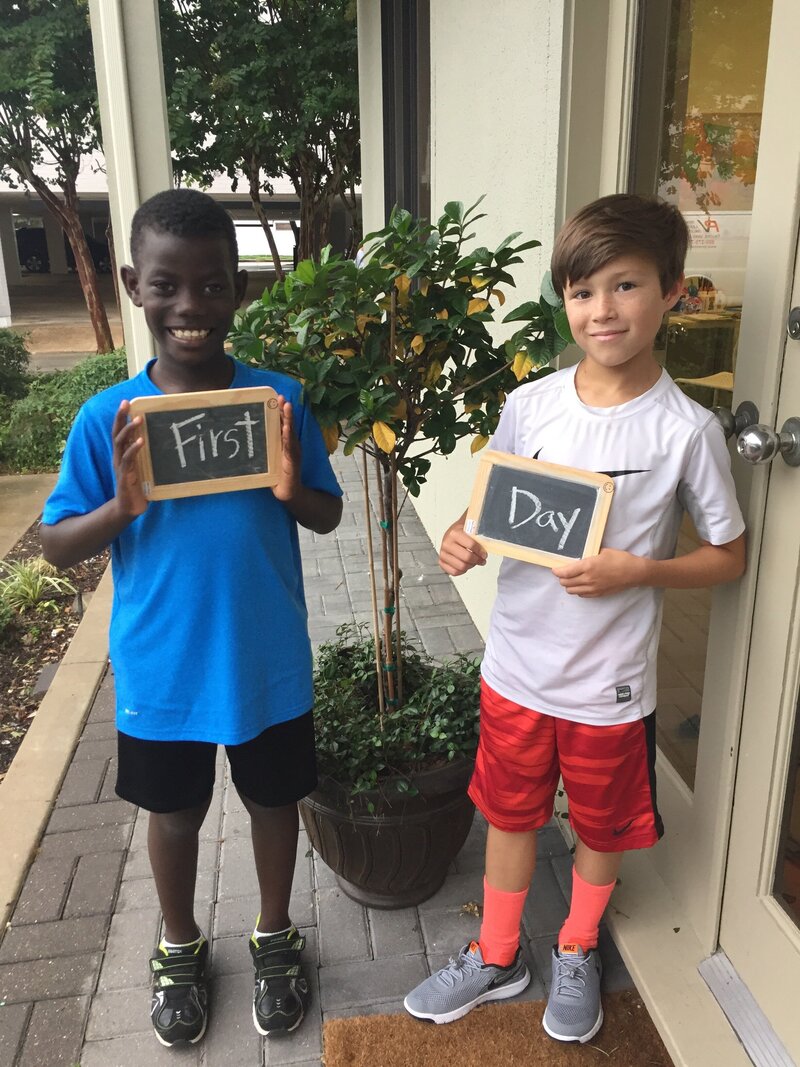 two students holding mini chalk boards on the first day of school