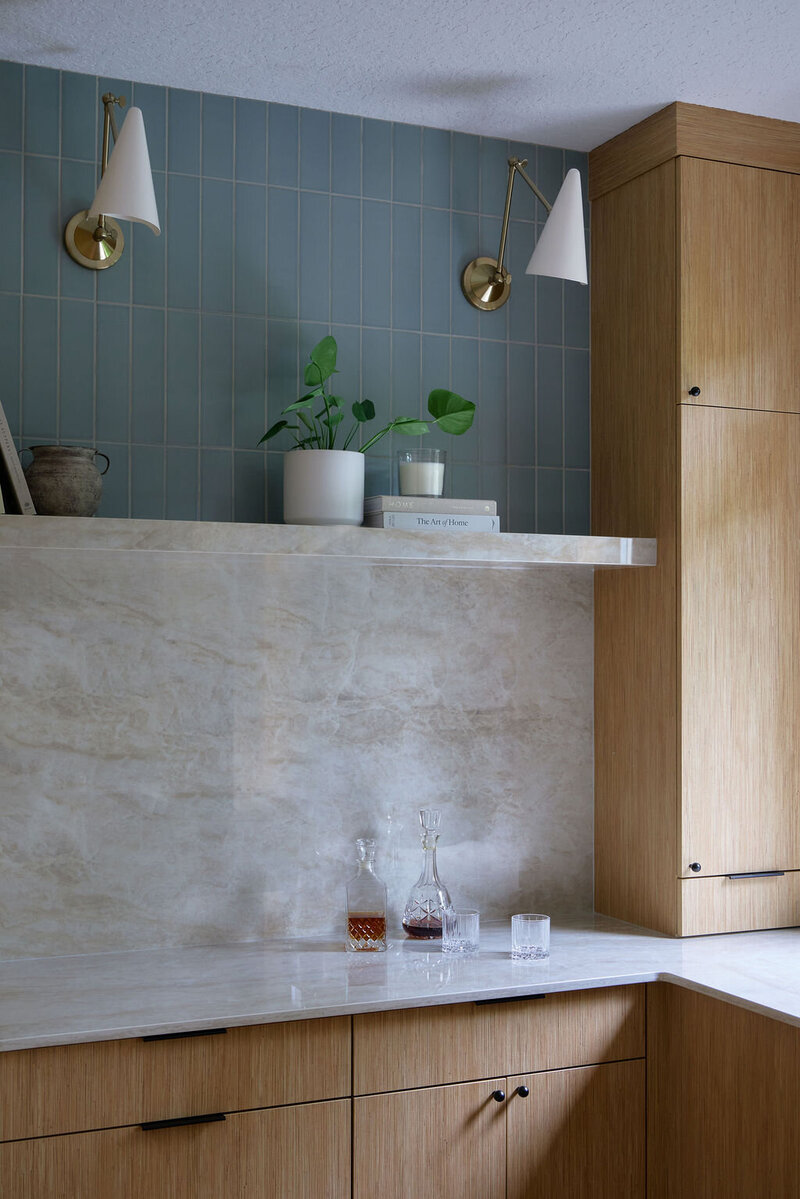 large mirror with black sconces, oak bathroom cabinets with black handles, white countertops