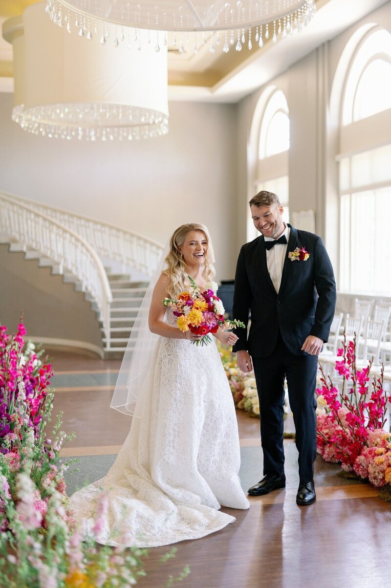 bride and groom pause with and around vibrant fuschia floral arrangements and bouquets for minneapolis wedding photographer bauer creative 