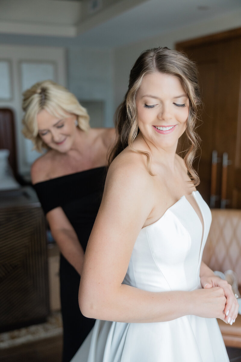 A bride with her mom getting zipped into her dress at the Ben in West Palm Beach. 