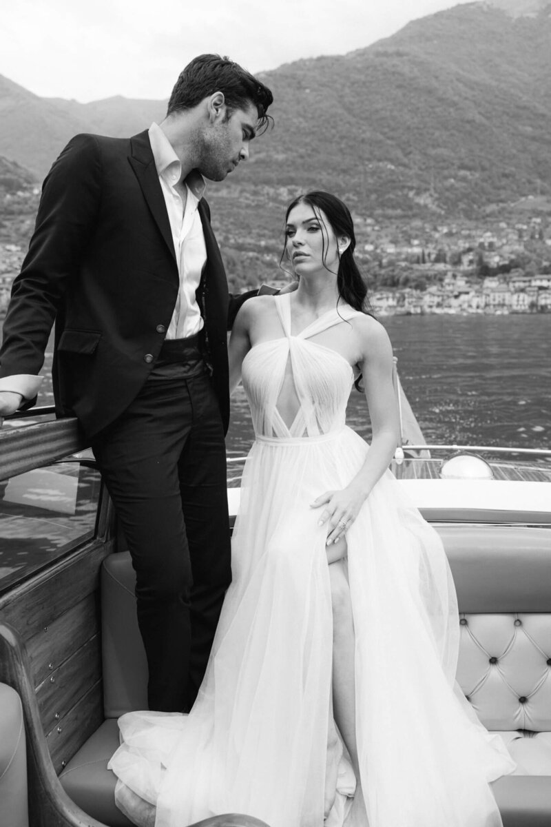 Candid  black and white wedding photo of a couple on a boat sitting beside each other on Lake Como in Italy