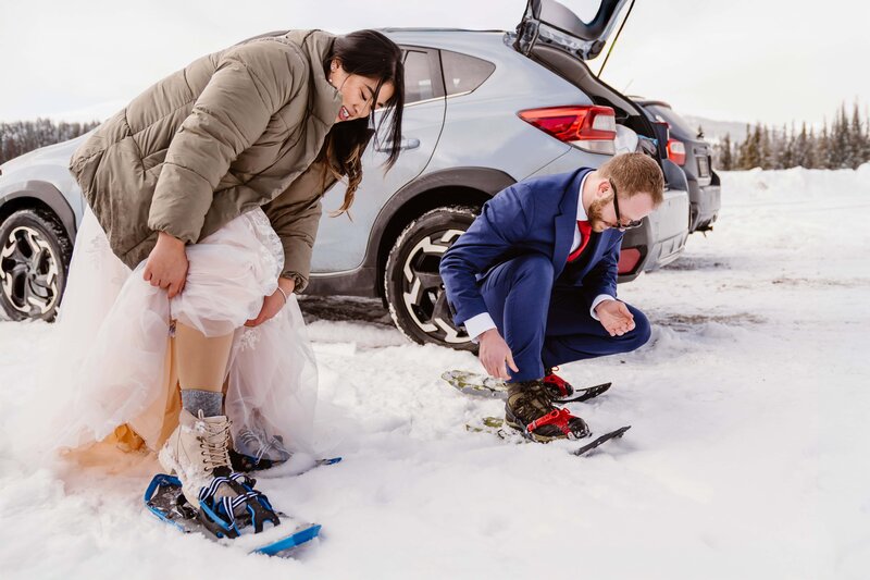 Couple puts on their snowshoes to get ready for their winter snowshoeing elopement in Breckenridge, Colorado with Colorado elopement photographer and videographer Alpine Vows
