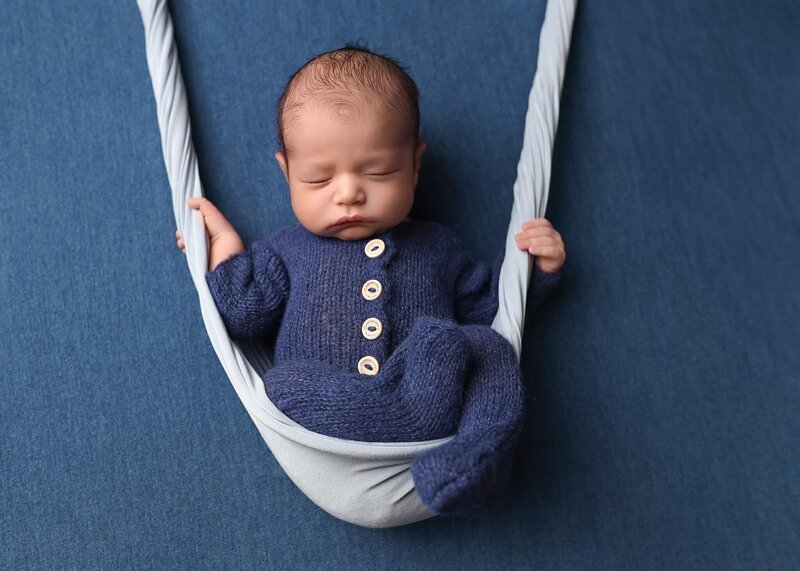 Baby sleeping in white wrap being carried away by a plush stork.
