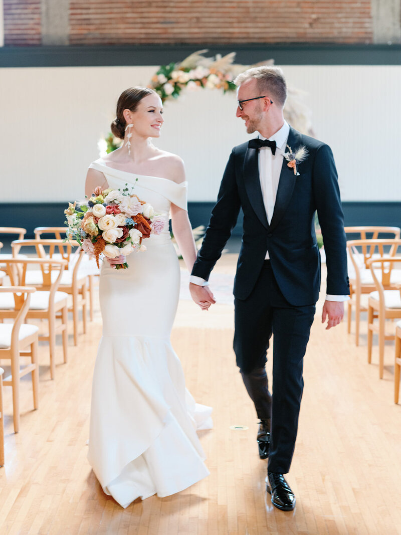 Bride and groom holding hands while walking
