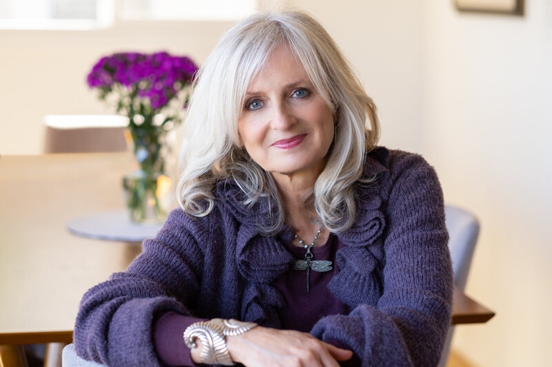 Jennifer Butler,  Intuitive Astrologer wearing purple sweater in an easy, relaxed pose