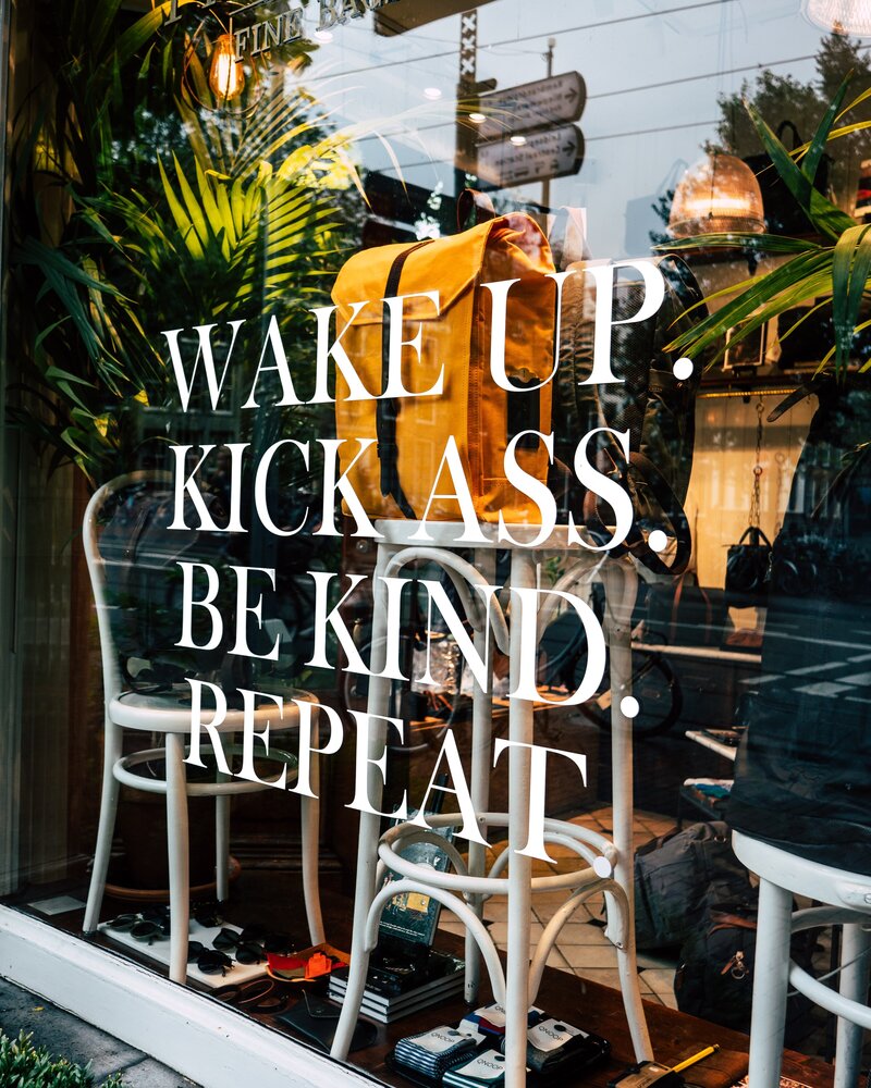 window display with sign that says wake up, kick ass, be kind, repeat - leo and vern