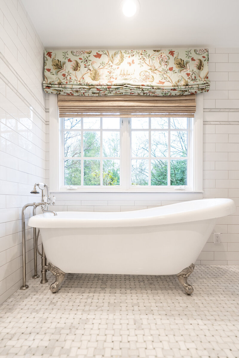 bathroom with white clawfoot tub and botanical window treatment