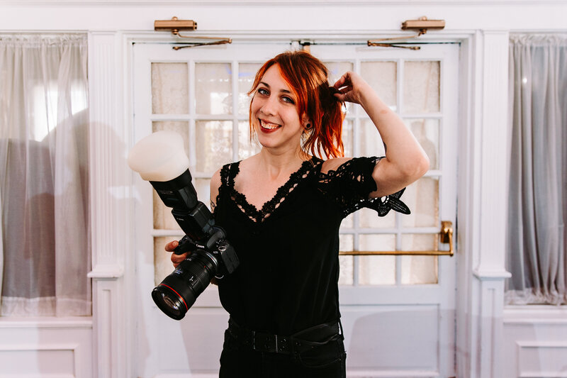 A wedding photographer with balloons in her hand and a goth aesthetic with a band tee