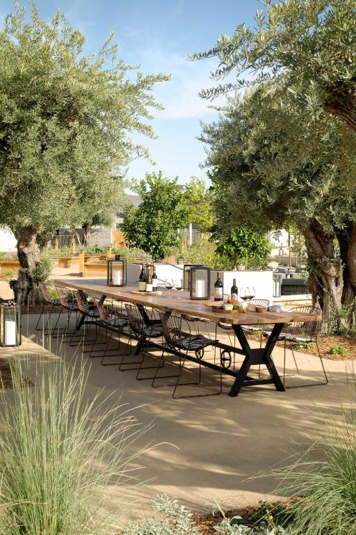 A beautifully set table featuring botanical-patterned linens, floral centerpieces, gold flatware, and green glassware.
