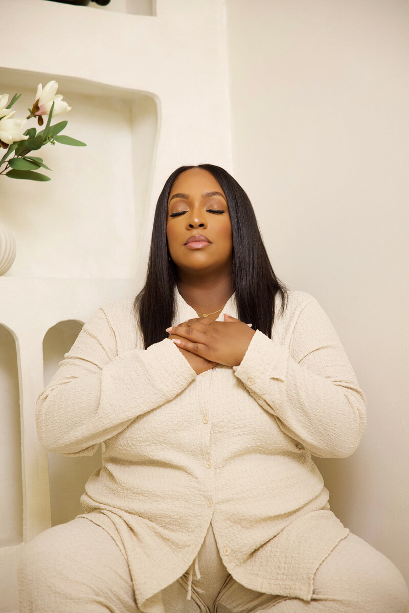 woman in white meditating with hand on chest