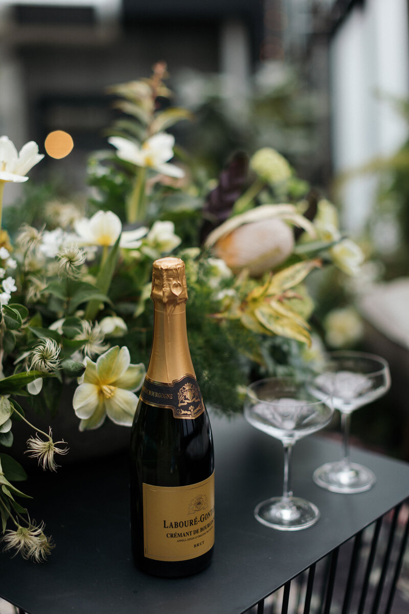 Champagne and coupes sitting on black coffee table Q Jancola