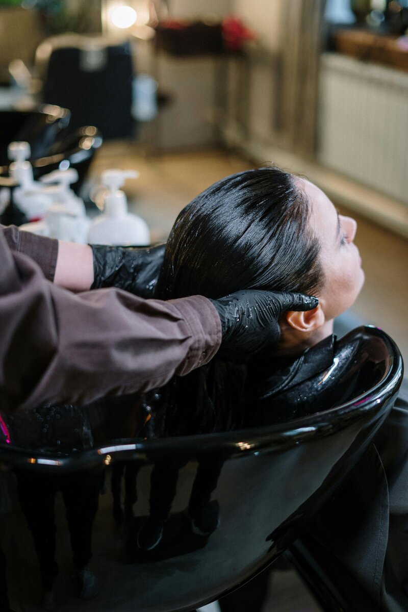 Client having hair rinsed in the shampoo washing bowl