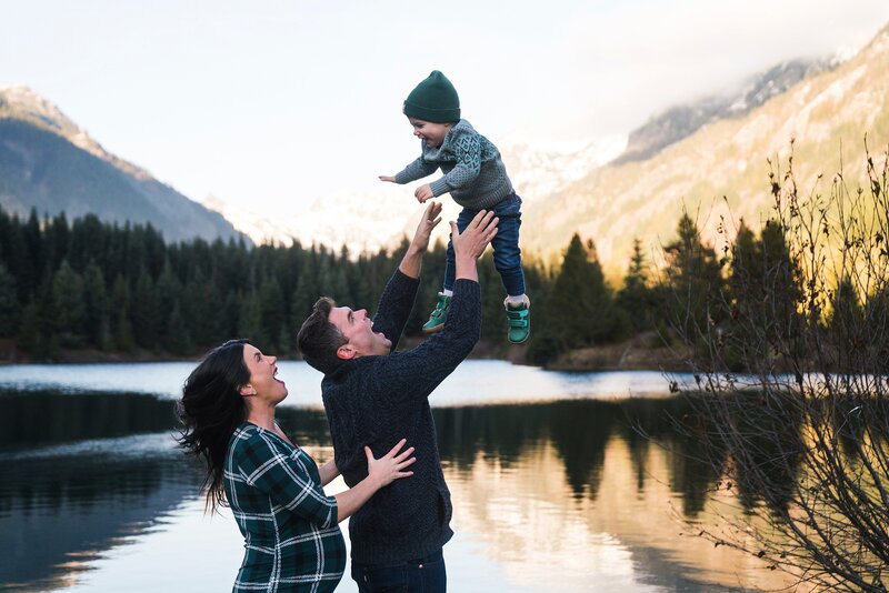 Snoqualmie pass maternity photo of father tossing toddler boy playfully into the air