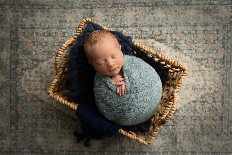 columbus-ohio-newborn-baby-boy-swaddled-in-dusty-blue-in-natural-woven-basket