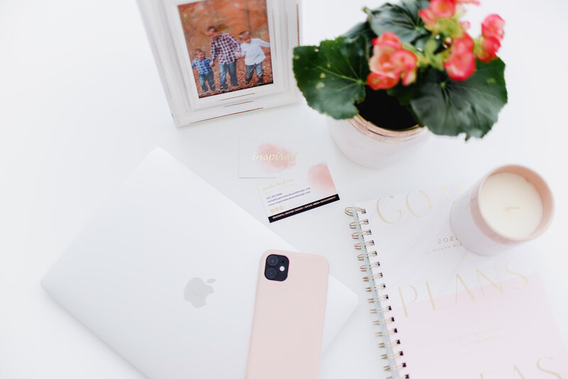 Computer sitting on desk beside vase of flowers