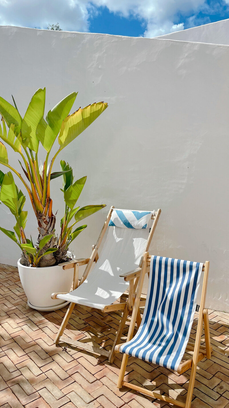 Two wooden deck chairs sitting on a brick patio