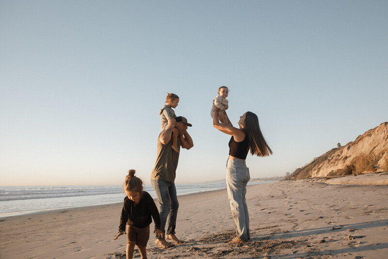 family plays on beach for family photos in san diego
