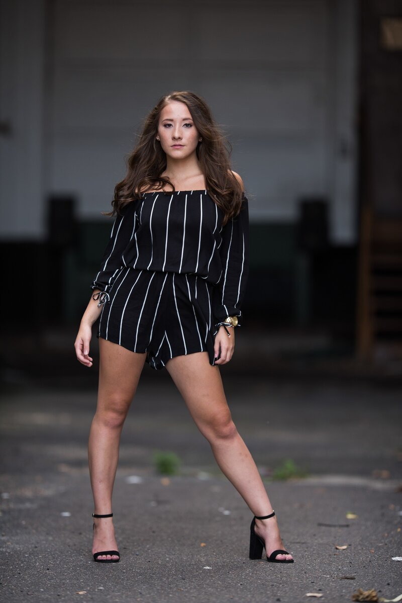 senior photo of girl in striped romper in grungy alley