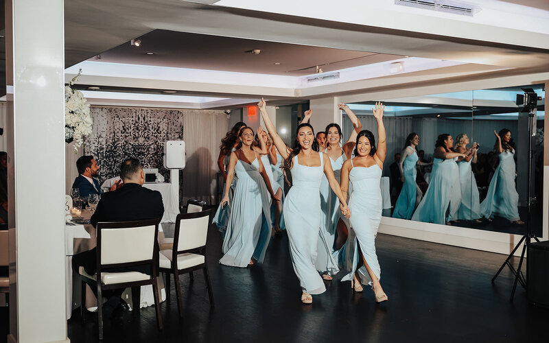 bridal party in matching light blue dresses enter wedding reception with energy