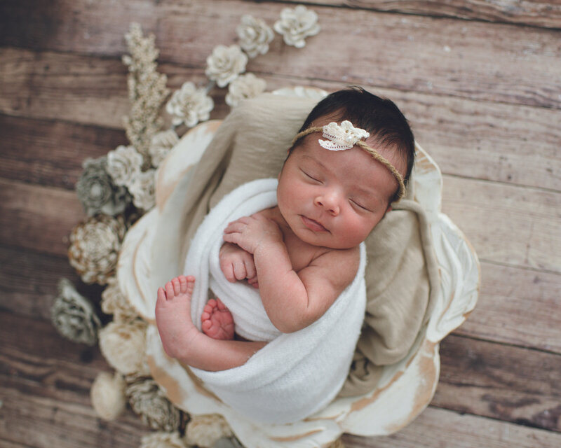 newborn baby girl wrapped in white with florals