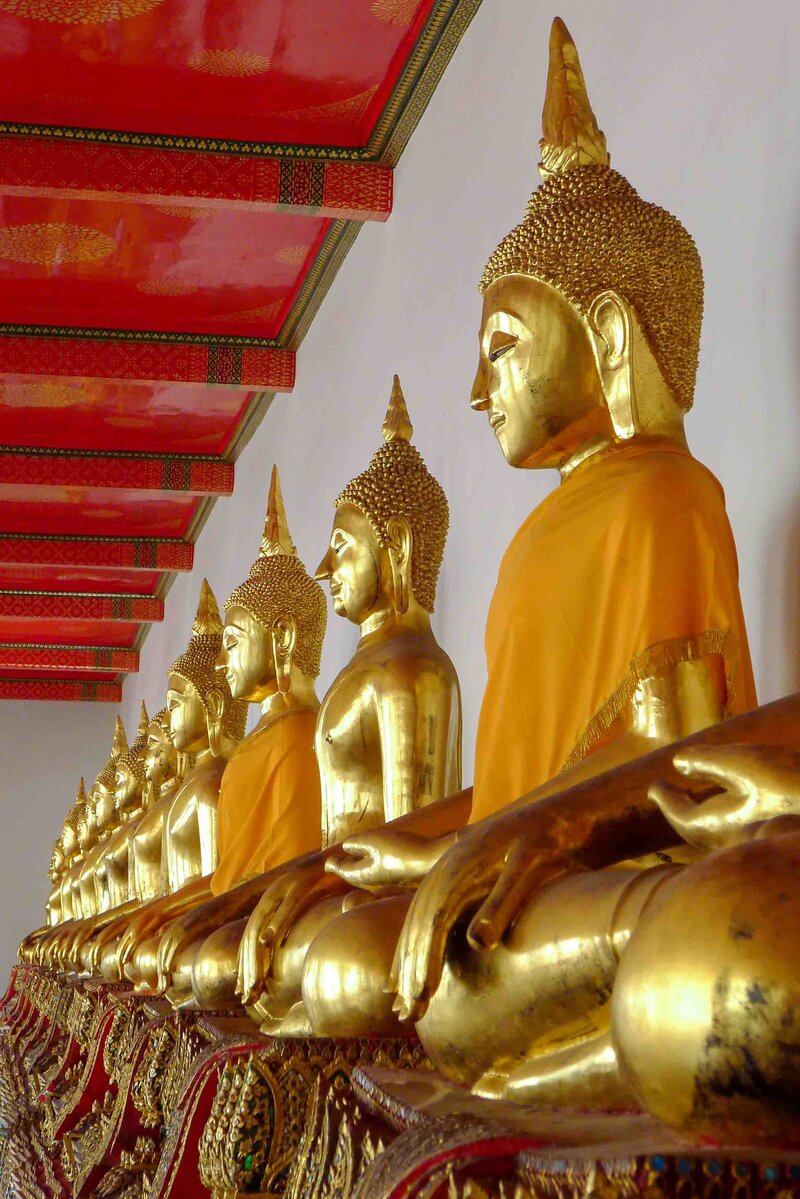 Changing to this: Row of golden Buddha statues draped in saffron robes at Wat Pho temple in Bangkok ©Stephanie Dosch | theViatrix Thailand Private Luxury Travel