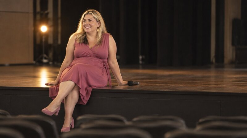 Renee Firth sitting on the edge of a stage