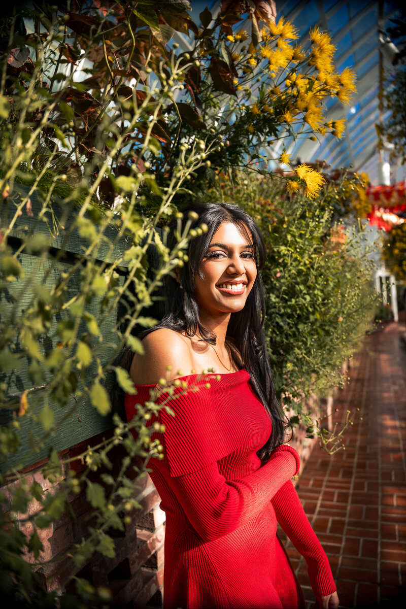 This striking image of a brown skinned senior standing in a patch of flowers inside Phipps.