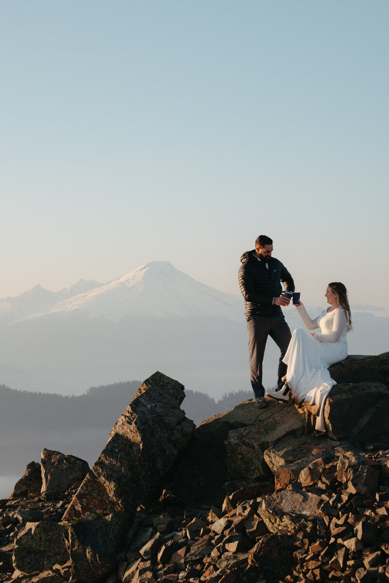 Bride and groom celebrate their hiking elopement by drinking champagne on a mountain